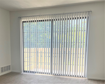 a large window with white vertical blinds in a living room